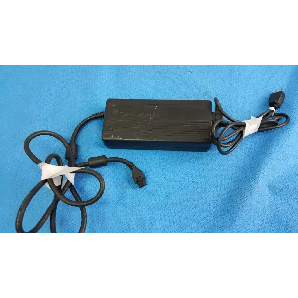 Black tyco electronics power adapter with coiled cables and white tape for electronics ac power supply use