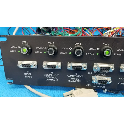 Black 19-inch rackmount control panel interface with four green-lit rotary switches and silver db9 serial ports