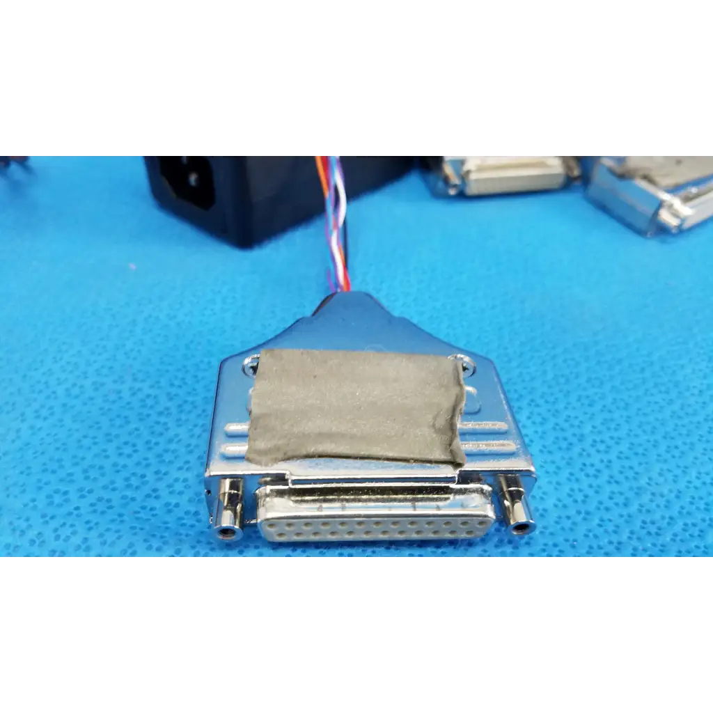 Silver metal d-sub connector with gray fabric patch and multicolored wires on 19-inch rackmount control panel interface