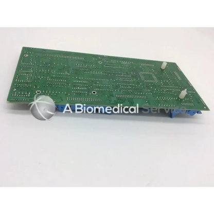 Green rectangular circuit board with silver solder points and blue connectors showing the back side of advanced input devices part 9200-12023-001/a
