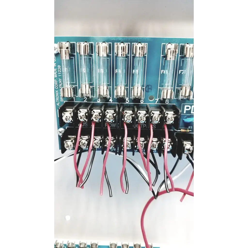 Blue circuit board of altronix smp5ctx high current power supply with eight glass fuses and red and black wire connections