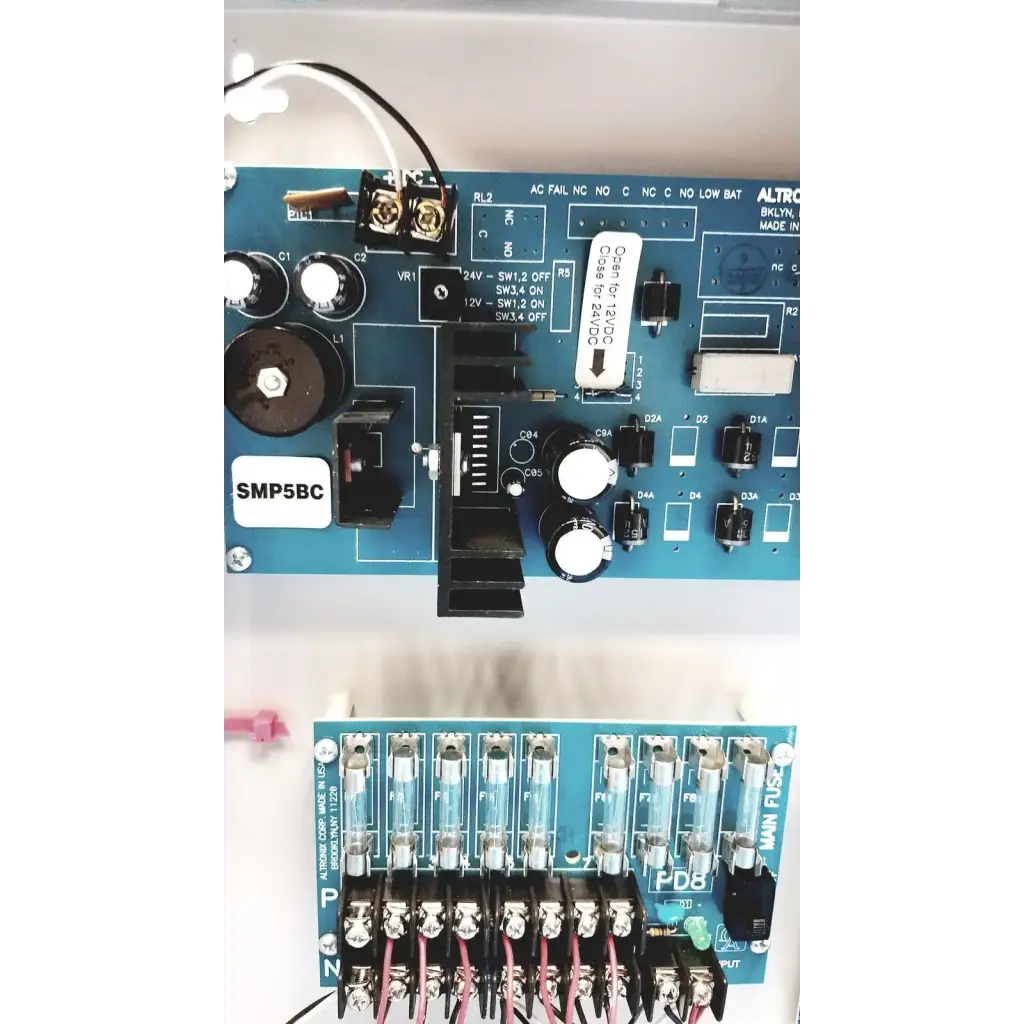Blue circuit board with white labels and black components of altronix smp5ctx high current power supply charger