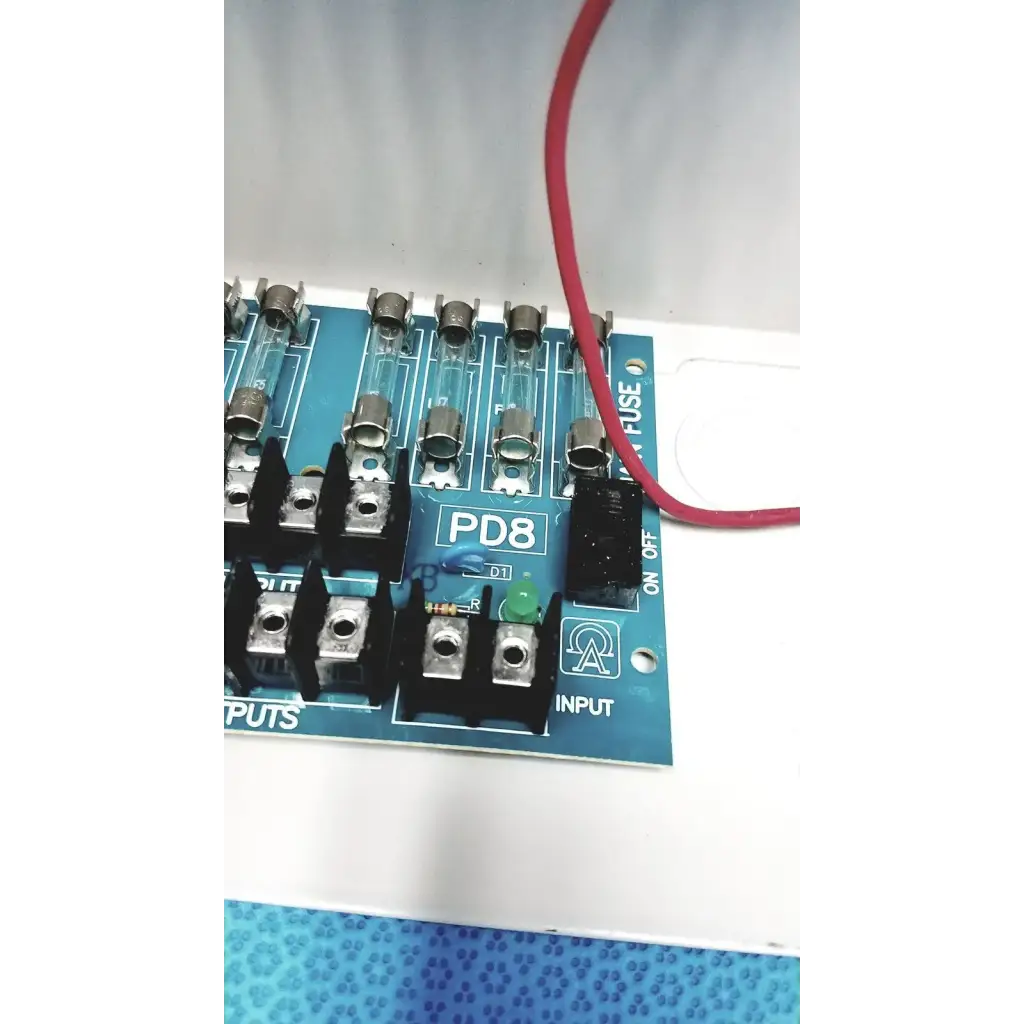 Blue pd8 circuit board with glass fuses and black terminal blocks in altronix smp5ctx high current power supply charger