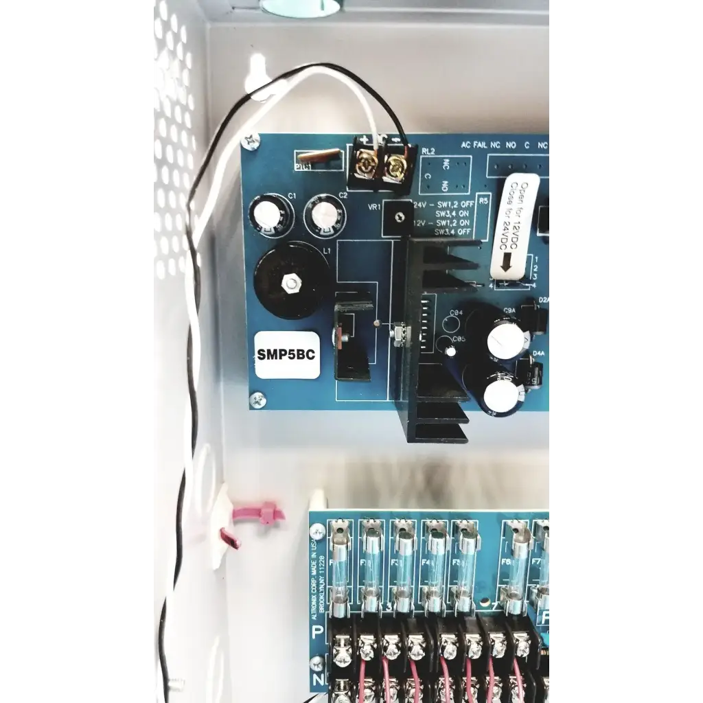 Blue smp5bc circuit board with white knobs and labeled components in altronix smp5ctx high current power supply charger