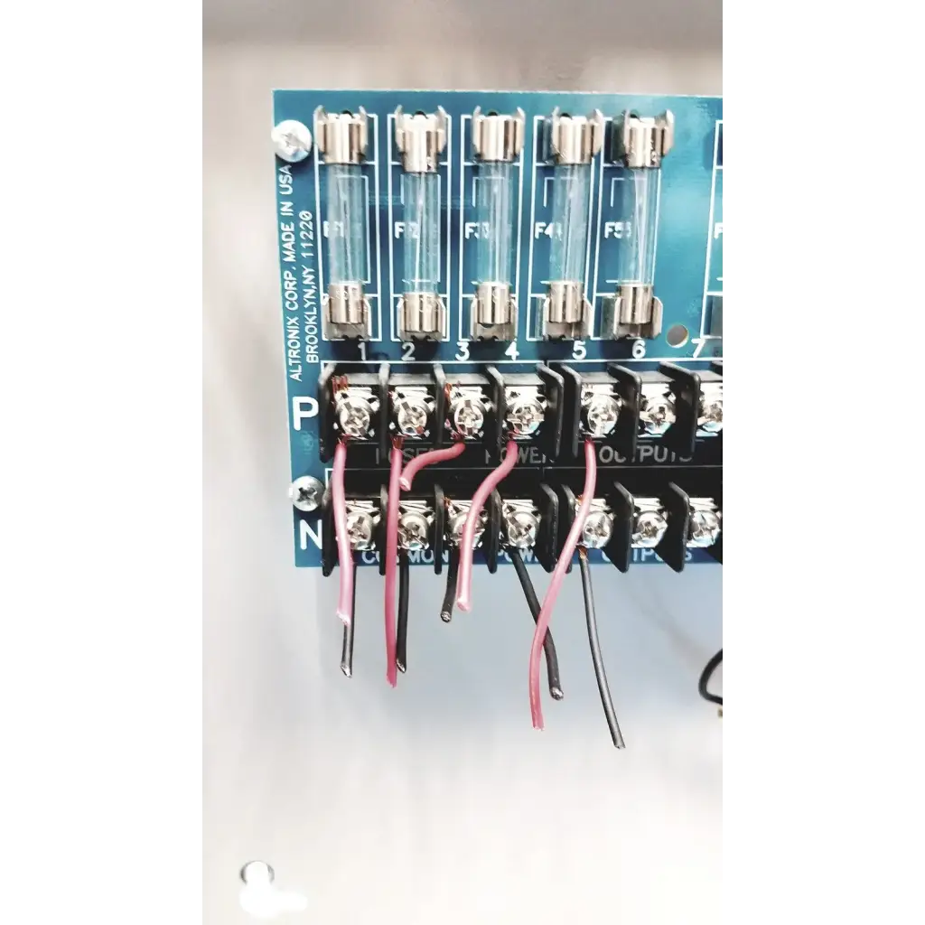 Blue altronix smp5ctx power supply circuit board with six glass fuses and black terminal blocks connected by pink and black wires