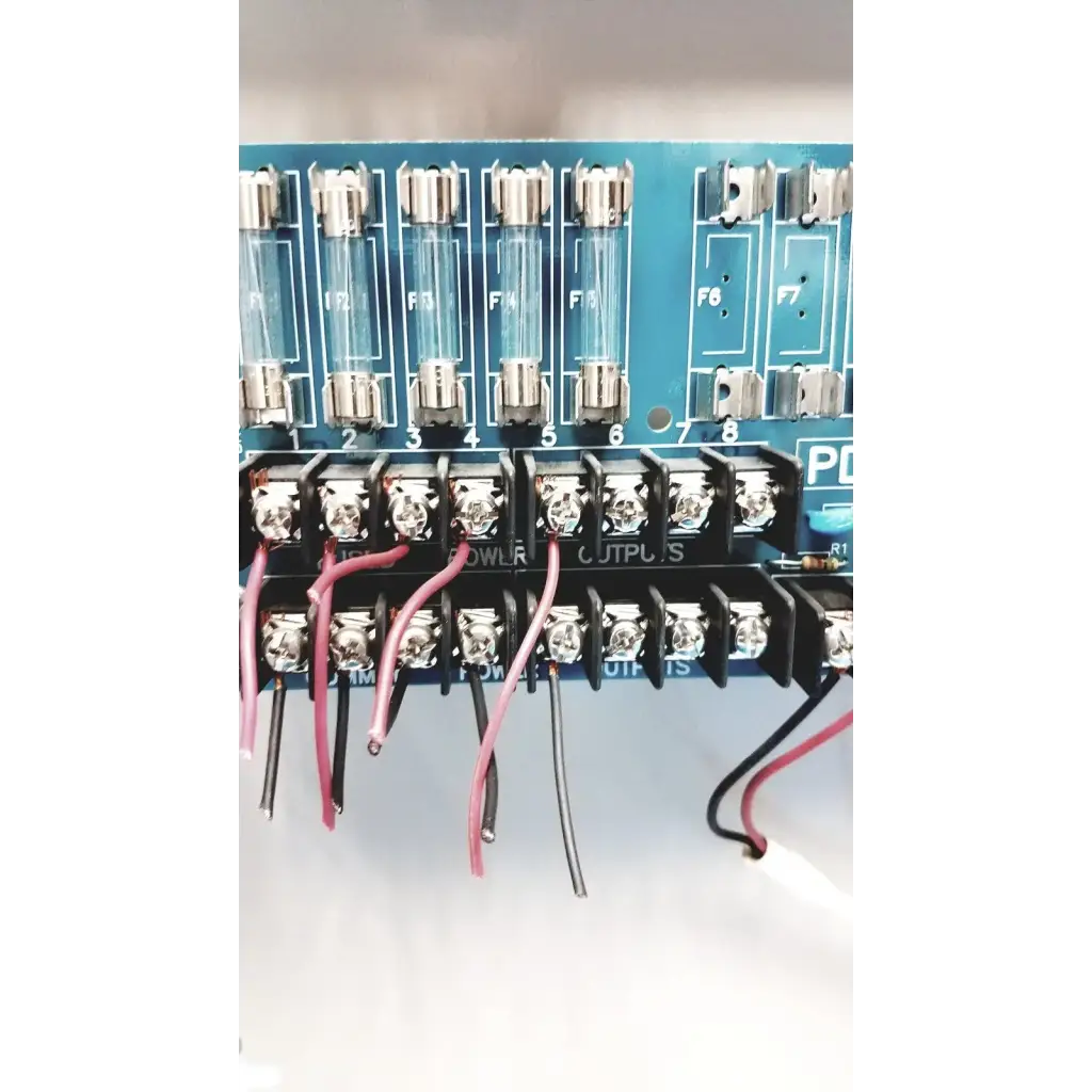Blue circuit board of altronix smp5ctx power supply with glass fuses f1-f8 and black terminal blocks for power outputs