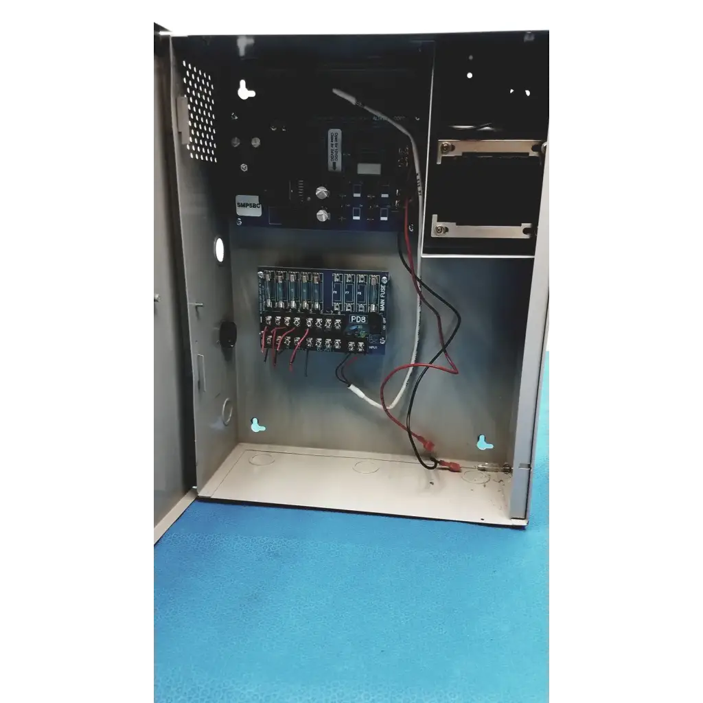 Metallic gray altronix smp5ctx power supply with blue circuit boards red and black wiring and white pdr label inside panel