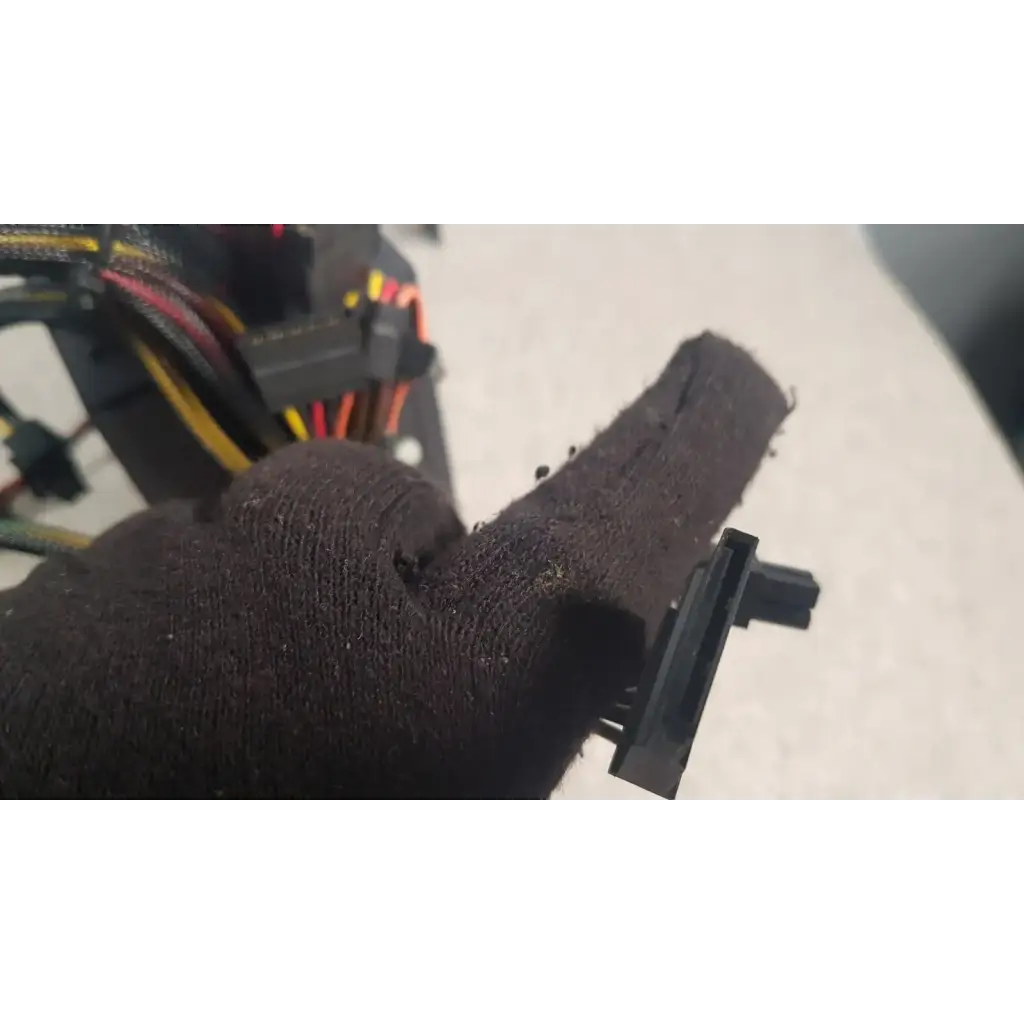Black textured fabric glove holding black plastic connector of antec truepower 550w black switching power supply