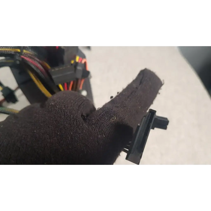 Black textured fabric glove holding black plastic connector of antec truepower 550w black switching power supply