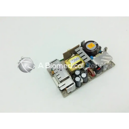 Silver and black electronic power supply board with capacitors and yellow transformer artesyn nlp65-9910 ac-dc model