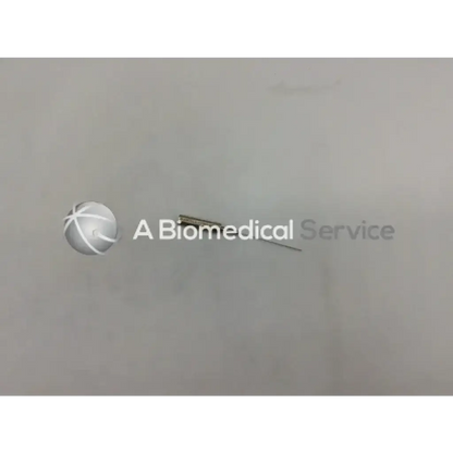 A metallic byron col-mini ii-s 070628-08 infiltration cannula style needle with slender shaft and pointed tip on plain surface