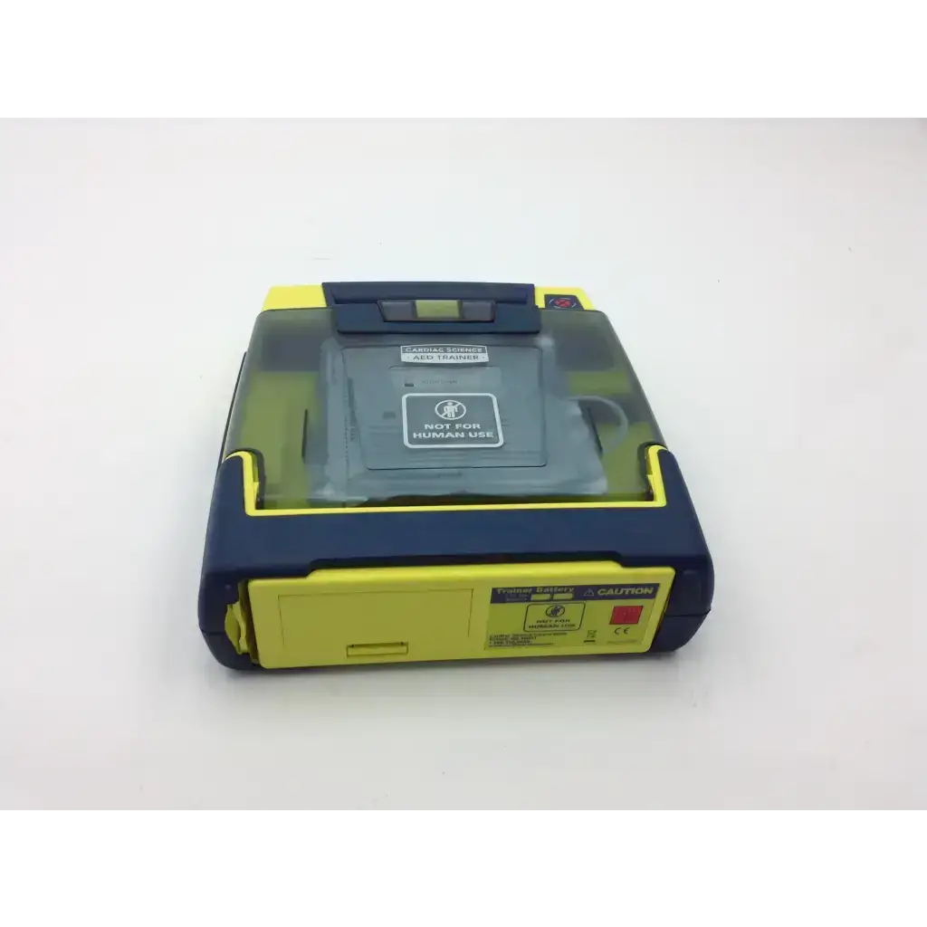 Yellow and navy blue cardiac science aed trainer with transparent lid showing internal components for training use