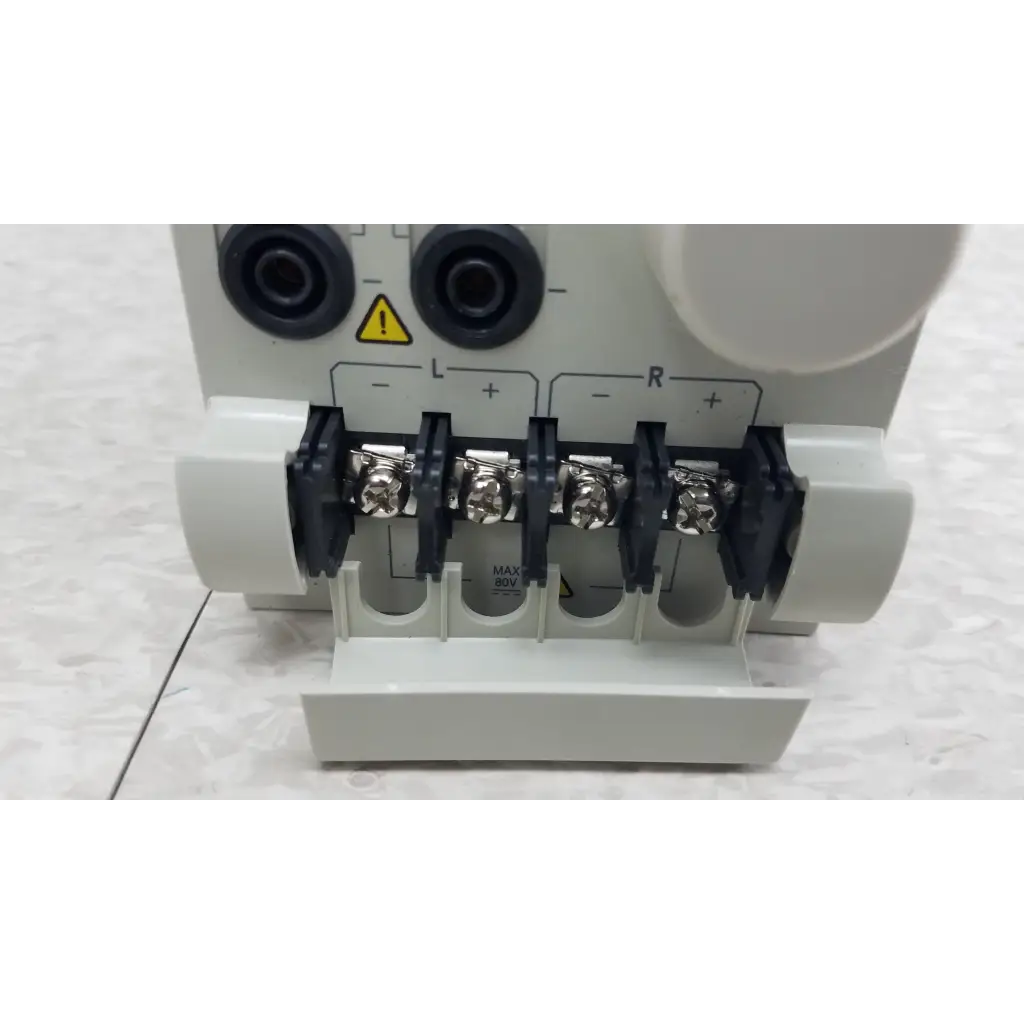 White plastic electrical terminal block with black insulated screws and silver connectors on chroma 63107 load module