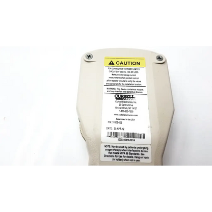 Off-white currell hospital pillow speaker with yellow caution label and black text showing specs and warnings on back side