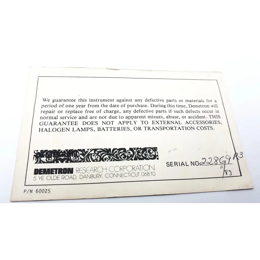 Off-white paper guarantee card from demetron research corporation with black text and decorative border for digilog electronic pulp tester