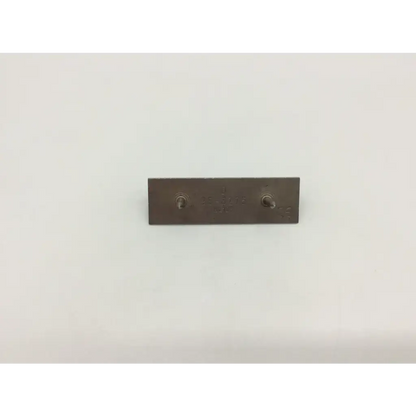 A dark gray metal rectangular femoral component trial pin with two circular fasteners for use in femoral component trials