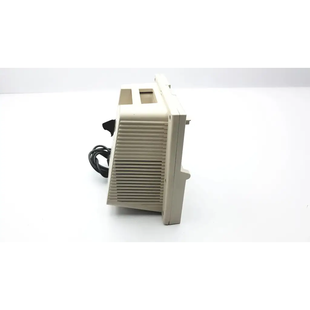 Beige plastic vintage computer monitor with vertical slatted ventilation grille and black power cord shown from the back with devilbiss pulmoaide compressor