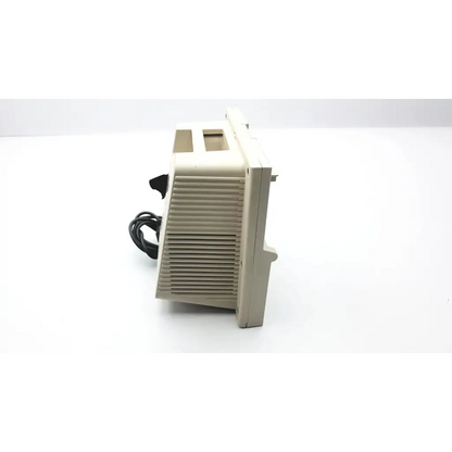 Beige plastic vintage computer monitor with vertical slatted ventilation grille and black power cord shown from the back with devilbiss pulmoaide compressor