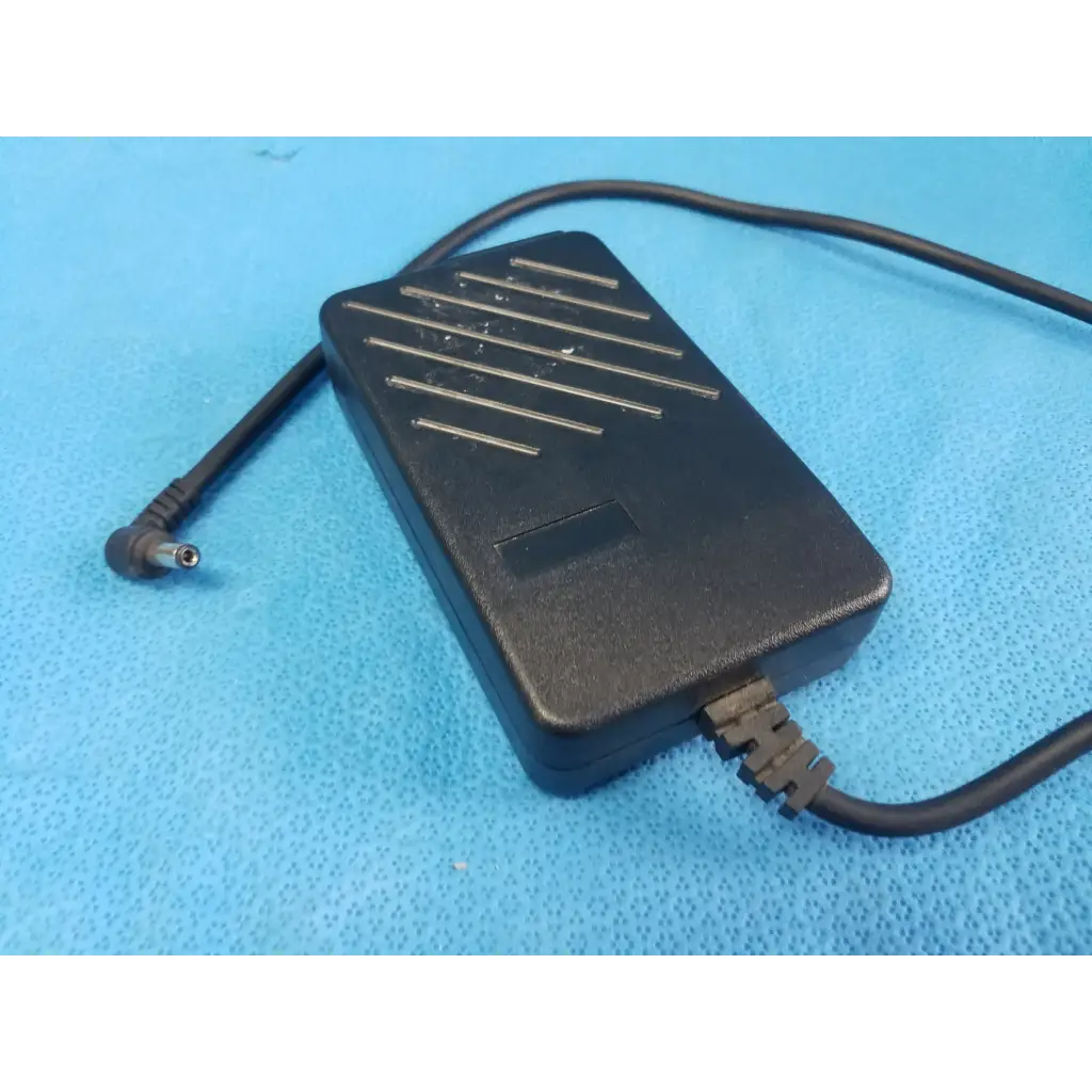 Black plastic power supply adapter with matte finish and silver ventilation slits for dinamap procare 3610 device