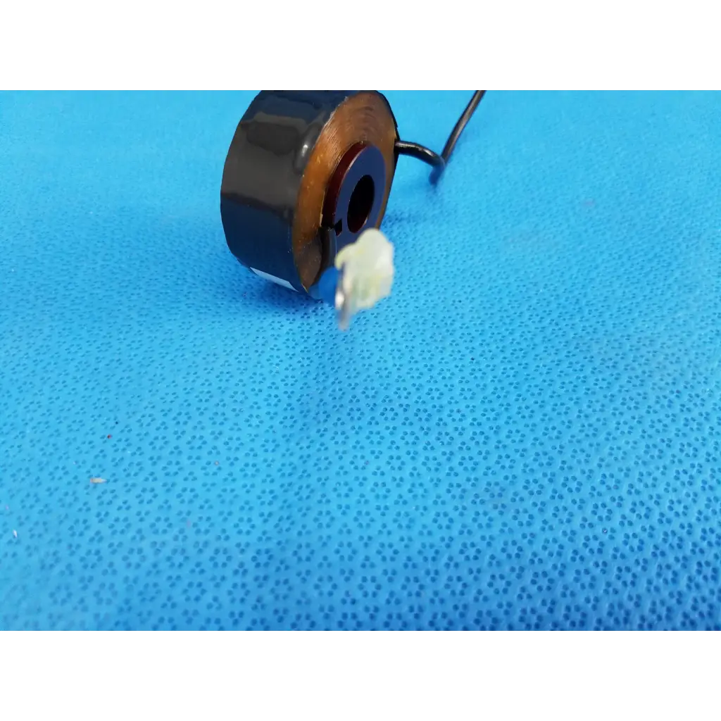 Black cylindrical toroidal current transformer sensor coil with copper windings and side wire for current measurement