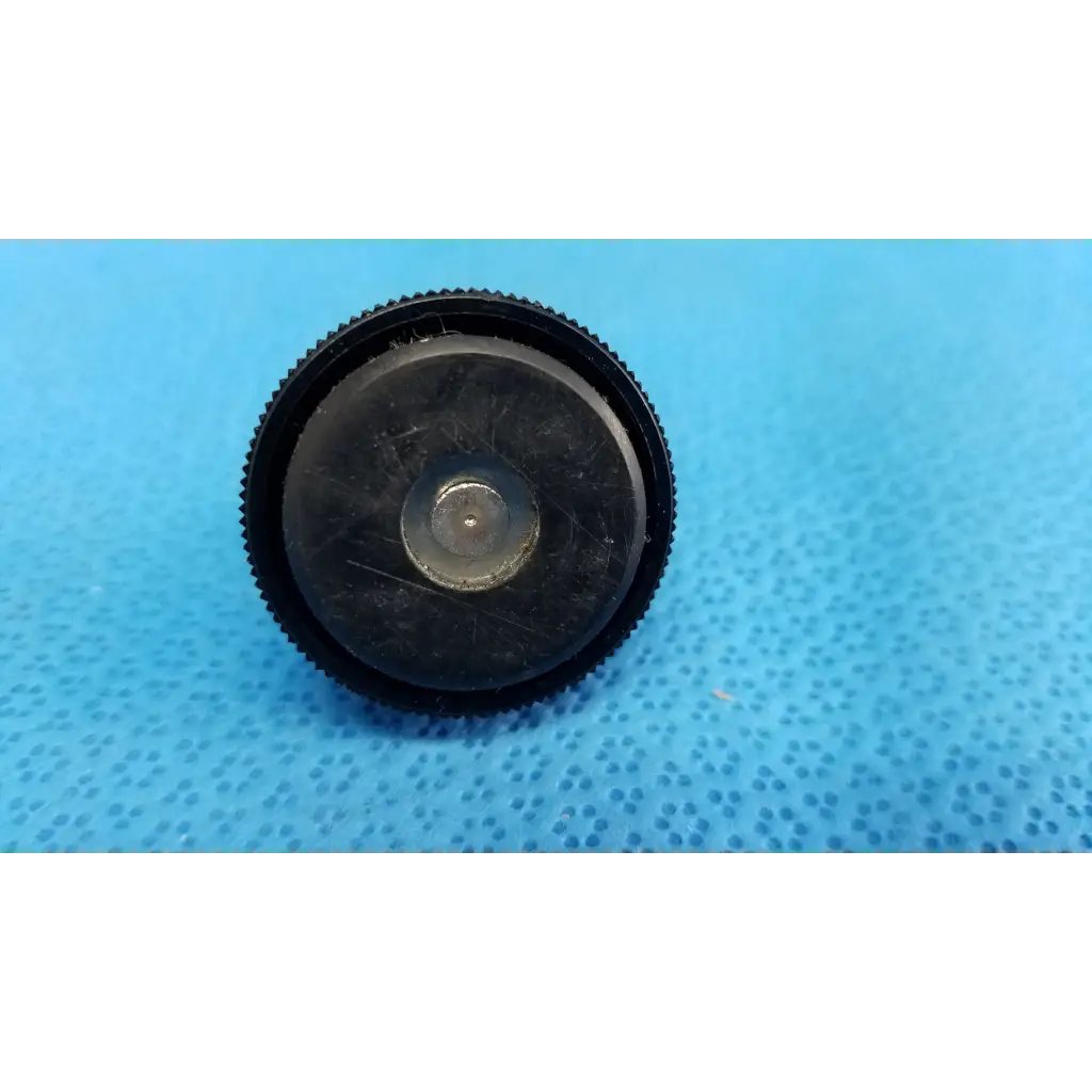 Black textured lens cap with central metallic ring for external mechanical leveling screw foot threaded bolt