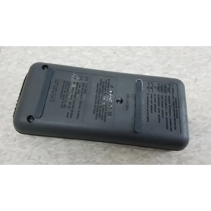 Back of gray plastic fluke 87 true rms digital handheld multimeter with printed specs and small circular button