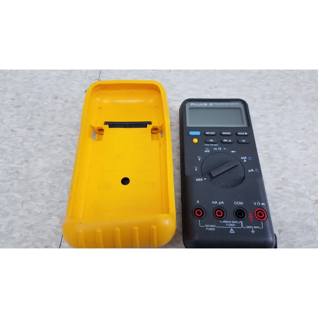 Black fluke 87 true rms digital handheld multimeter with red and black test leads next to yellow protective case