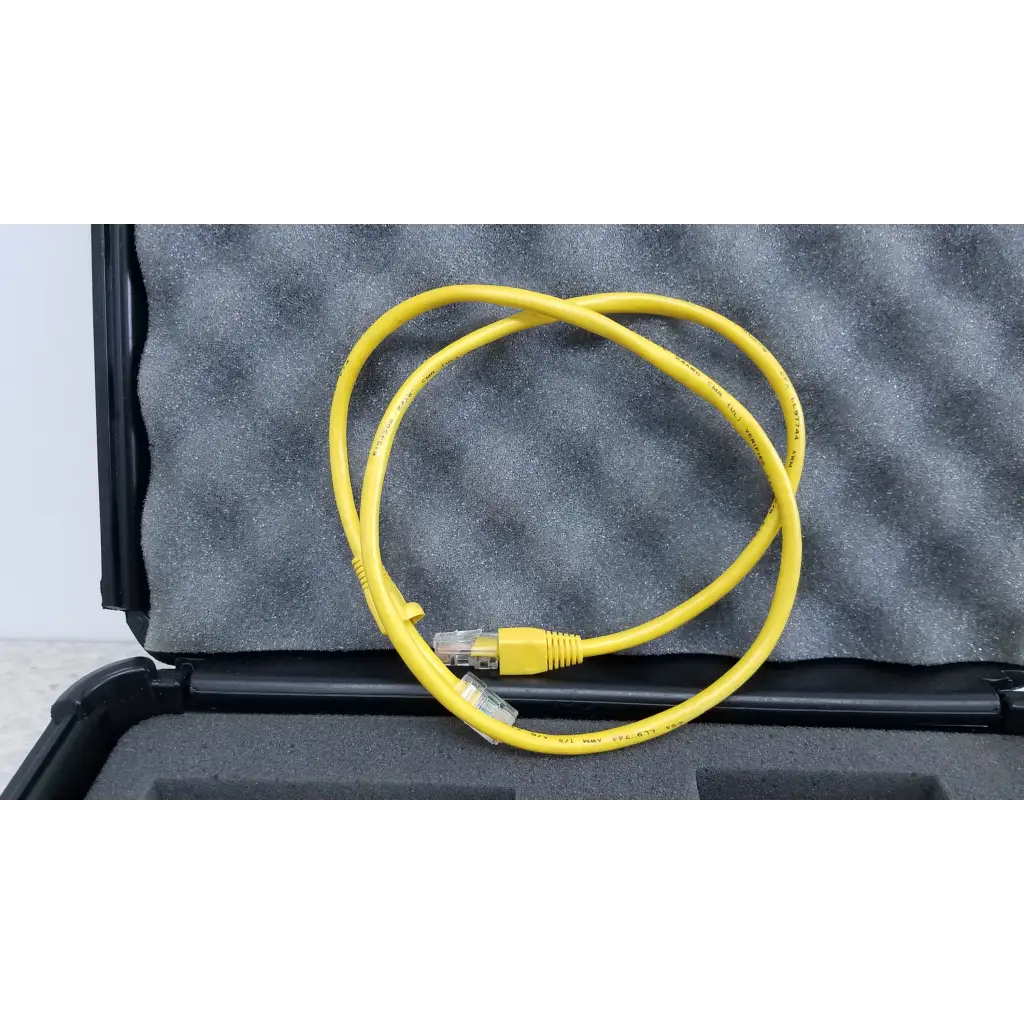 Yellow ethernet cable with clear rj45 connectors coiled in black foam-lined case for fluke networks fiber optic source