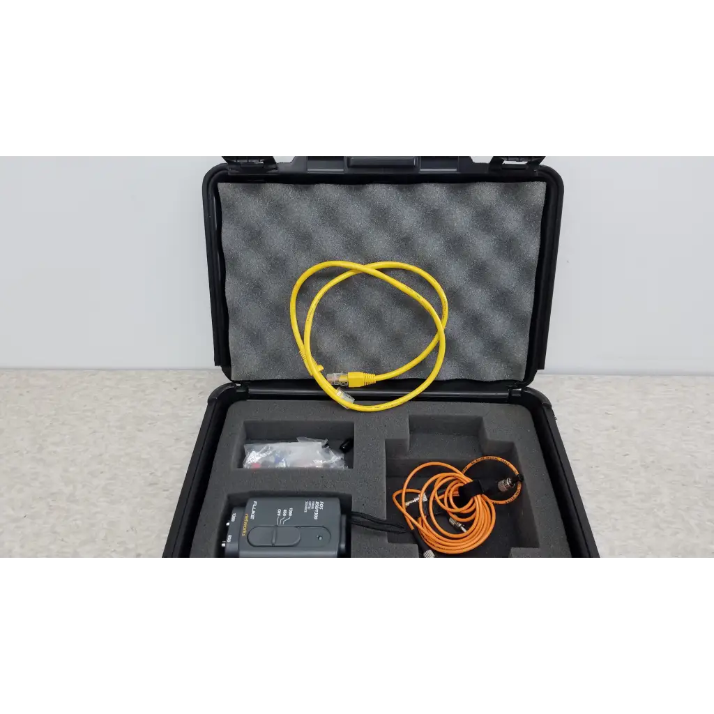 Black rugged case with fluke networks fiber optic source and yellow ethernet and orange coiled cables in foam slots