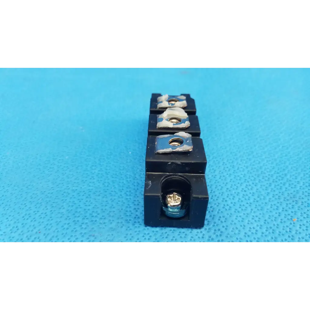 Black plastic electrical terminal block with four slots and screws on fuji electric dual diode power diode module