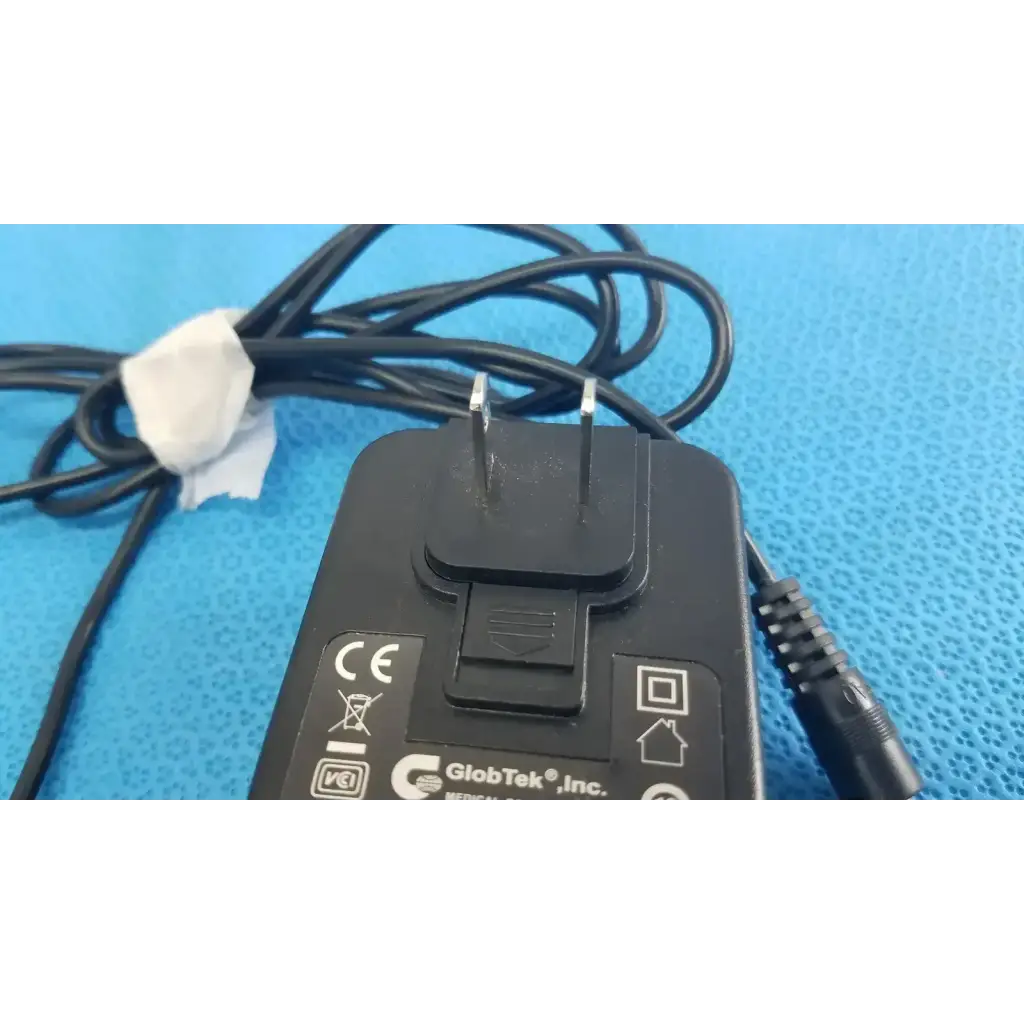 Black plastic globtek gtm41060-1505 medical power supply with coiled cable secured by white paper tie for medical power
