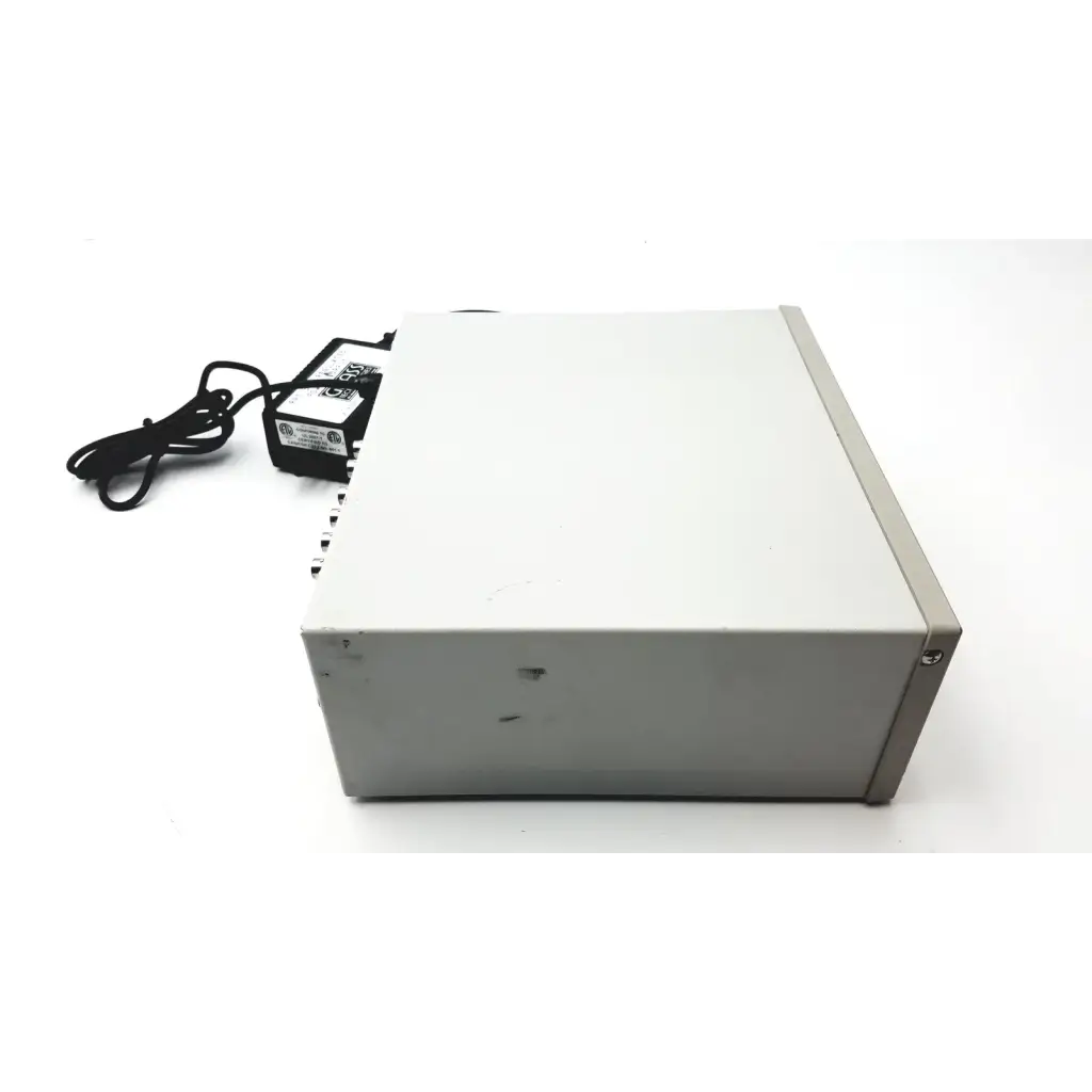Gray rectangular grass 15lt physiodata 15a54 quad amplifier system with black power adapter and cord nearby