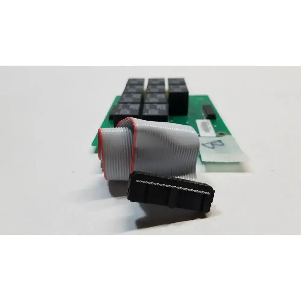 Gray ribbon cable with red edge and black connector in front of green hill rom total care sidecomm ent light control board