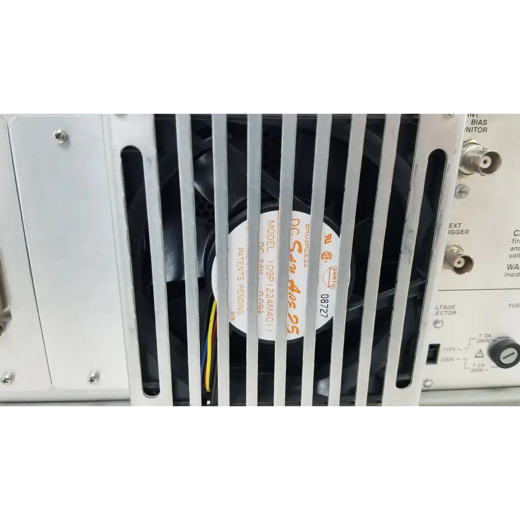 Silver fan with black blades and a white label with orange text inside metal grille on hewlett packard precision lcr meter