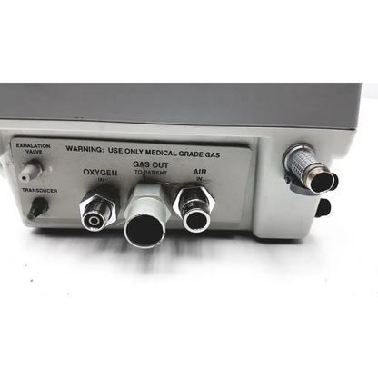 Gray medical gas delivery unit with labeled oxygen air and transducer ports on back of impact instrumentation uni-vent 754 portable ventilator