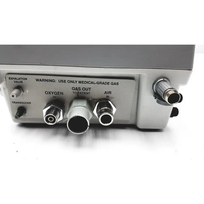 Gray medical gas delivery unit with labeled oxygen air and transducer ports on back of impact instrumentation portable ventilator
