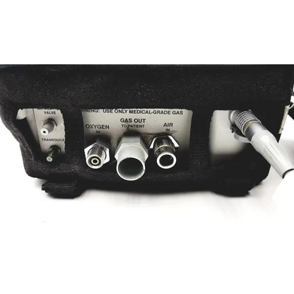 Back side of impact instrumentation inc uni-vent 754 portable ventilator showing labeled oxygen and air ports with metallic connectors and black casing