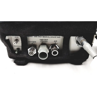 Black medical gas delivery device with metallic connectors and labeled oxygen and air ports on impact instrumentation portable ventilator