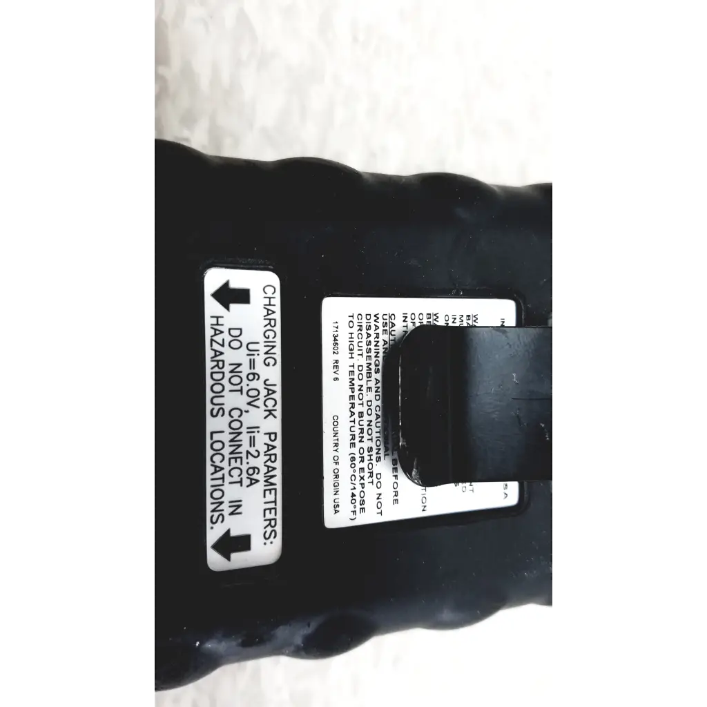 Black plastic battery with white label showing charging parameters on the back side of industrial scientific ibrid mx6 multi gas monitor with charger