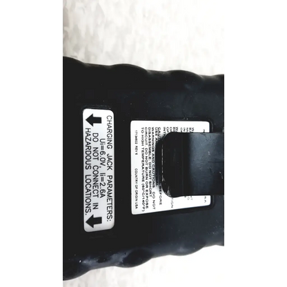 Black plastic battery with white label showing charging parameters on the back side of industrial scientific ibrid mx6 multi gas monitor with charger