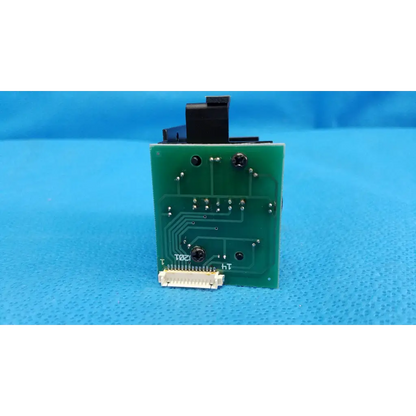 Green rectangular circuit board with black components and white connector for internal fixation target in topcon retinal camera