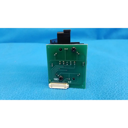 Green rectangular circuit board with black components and white connector for internal fixation target in topcon retinal camera