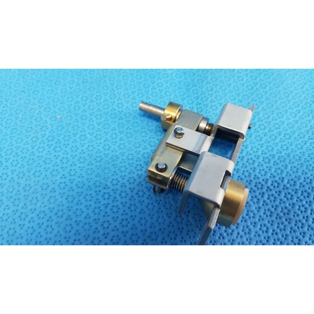 Silver and brass mechanical assembly with spring-loaded lever and plunger pin for main unit locking knob of topcon retinal camera