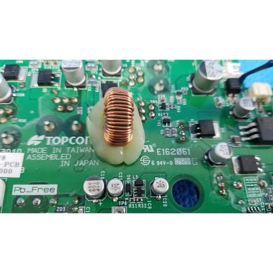 A copper-colored coiled wire inductor on a green power PCB for internal DC power in Topcon fundus camera