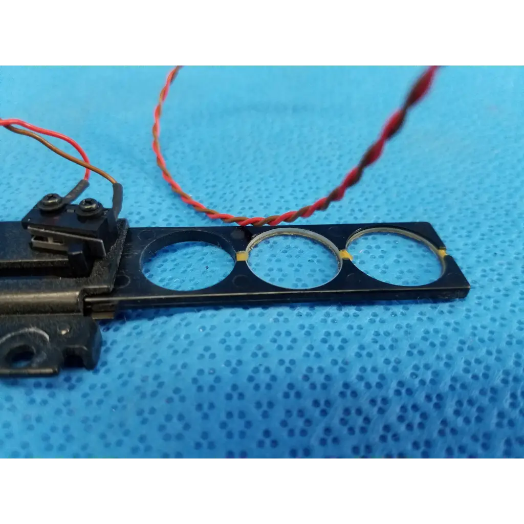 Black rectangular diopter slider lens assembly with three circular cutouts and red-black twisted wires for Topcon retinal camera