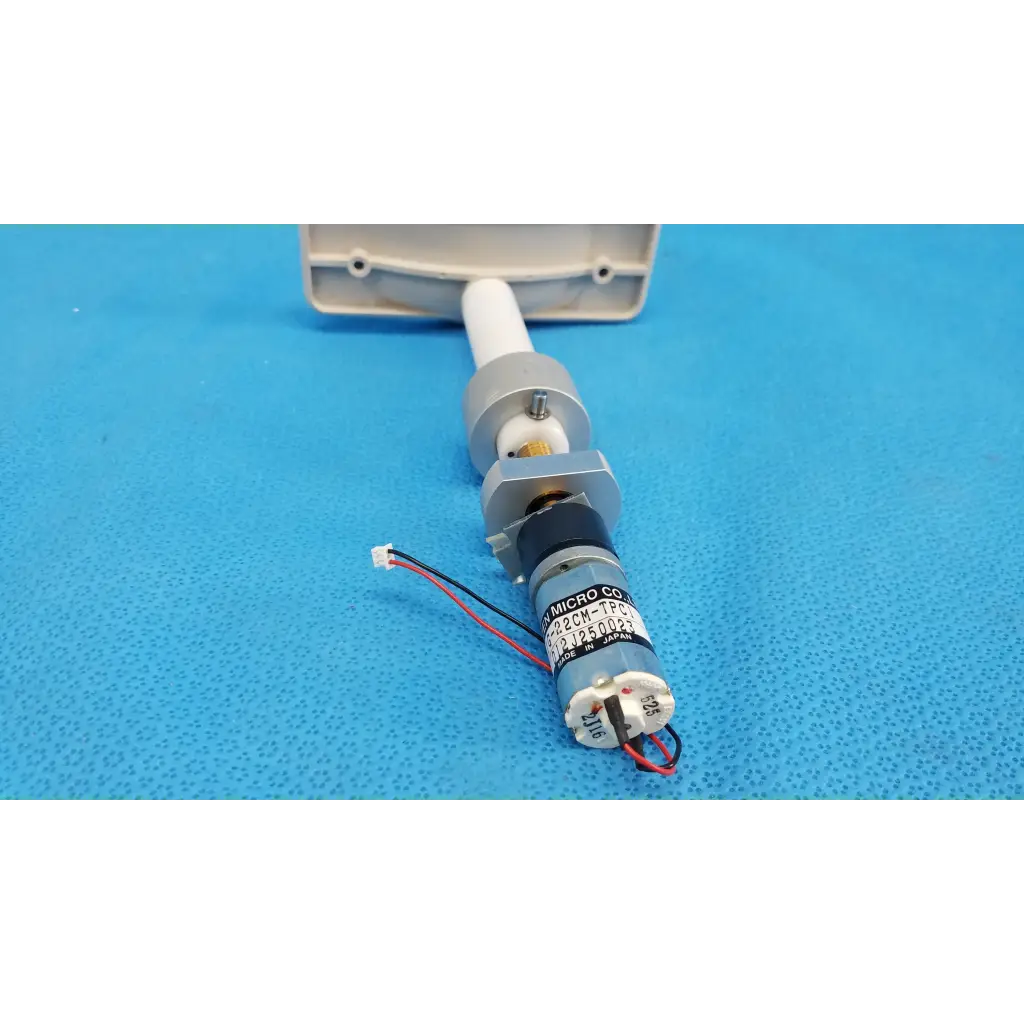 Gray cylindrical micro gear motor with black and white wiring labeled micro co for motorized chinrest assembly