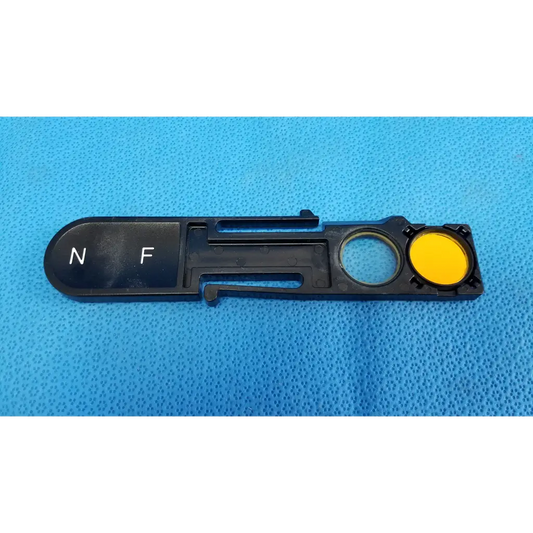 Black plastic optical filter slider with yellow circular component and white n f markings for topcon fundus retinal camera