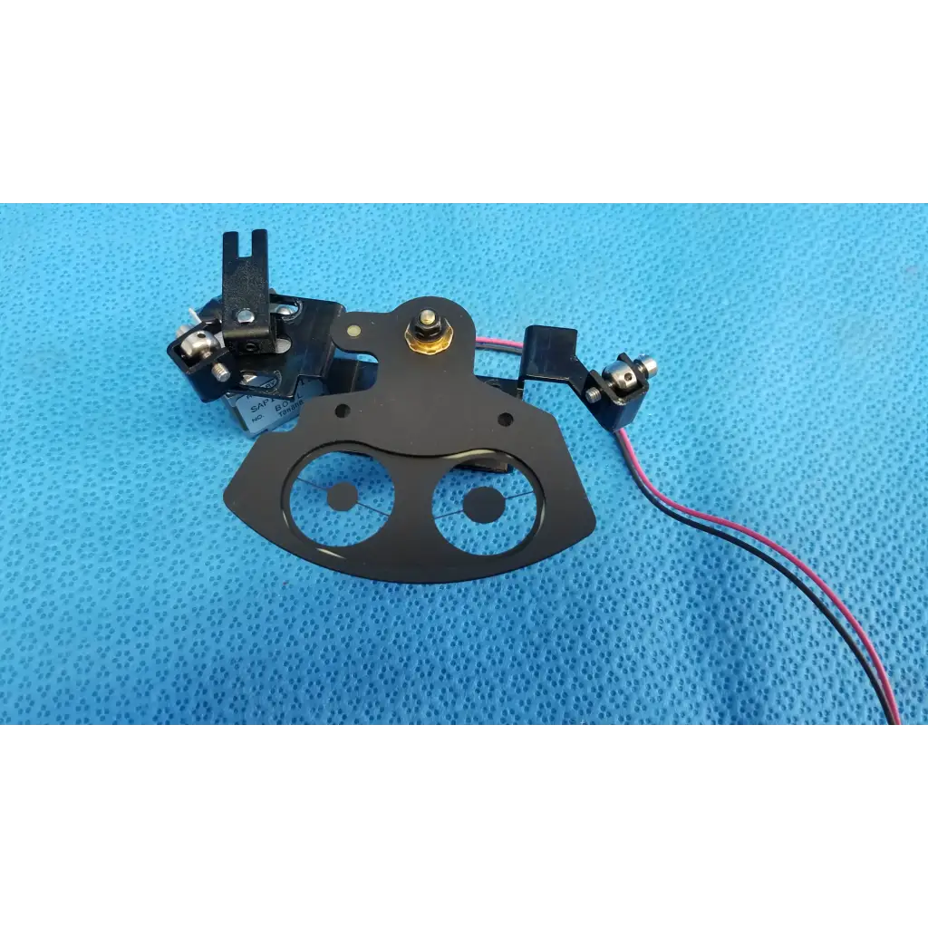 Black metal rotary solenoid aperture diaphragm presser foot with circular cutouts and wiring for topcon fundus camera