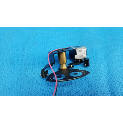 Black and brass rotary solenoid aperture diaphragm labeled globel 1908 mounted on black plastic base for topcon camera