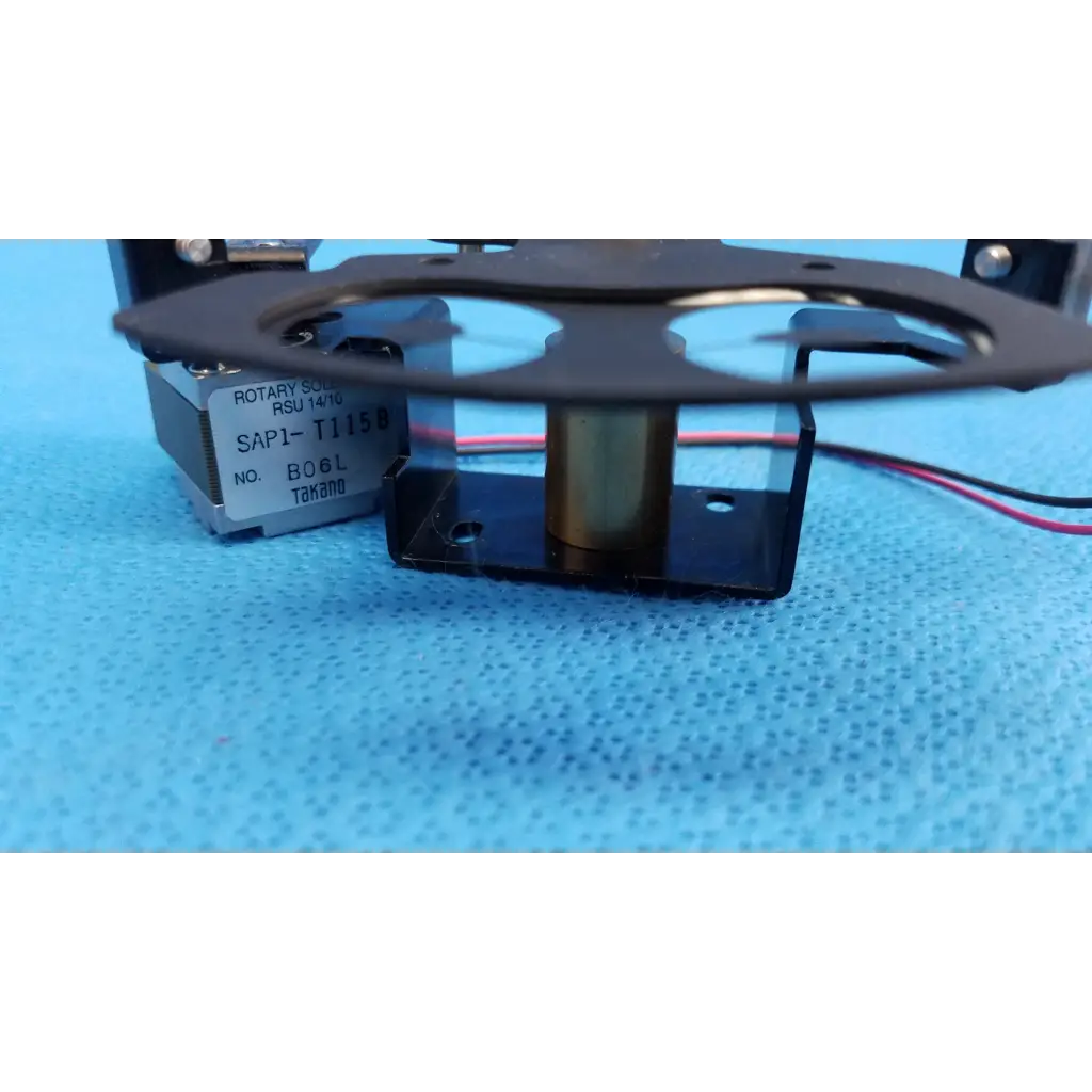 Black rotary solenoid aperture diaphragm switch with metallic center labeled sap1 t1158 on silver base for topcon camera